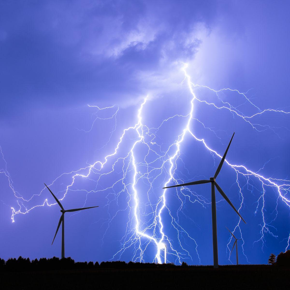 Thunderstorm with lightning strikes and wind turbines.