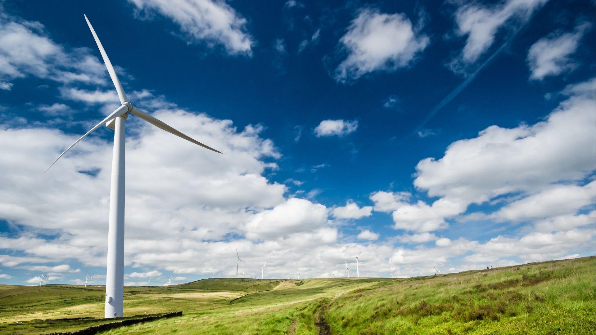 Wind farm with a cloudy blue sky.
