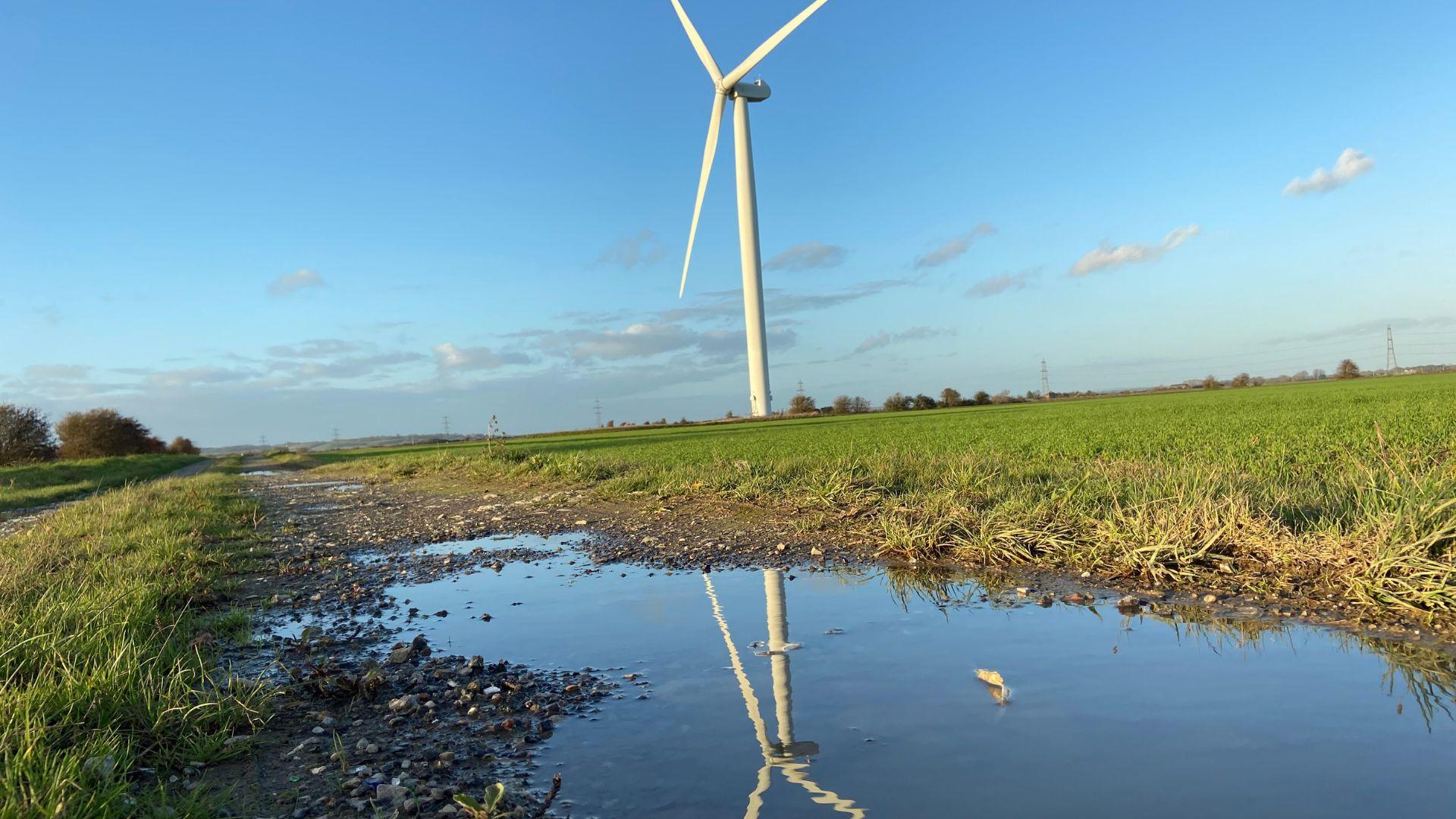 Wind turbine with reflection in the water. Copyright: cheekylorns/Getty Image/Canva