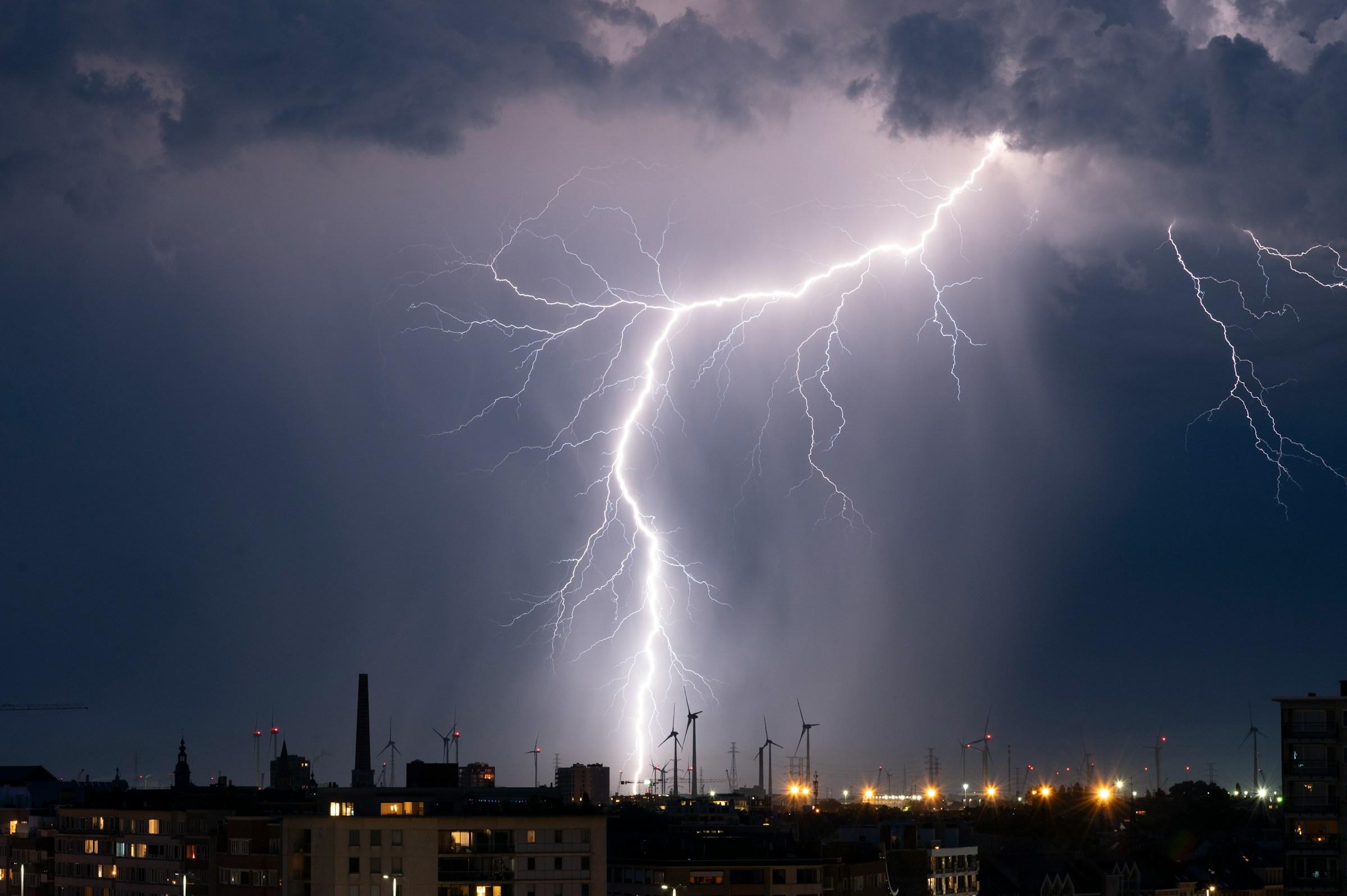 Lightning striking over a dark landscape during a night thunderstorm